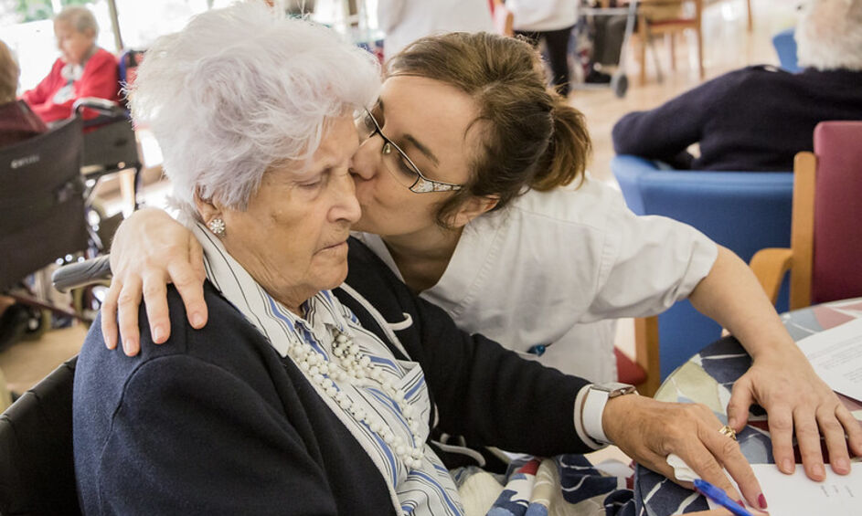 Infermera geriàtrica fa un petó a una dona resident en un centre geriàtric